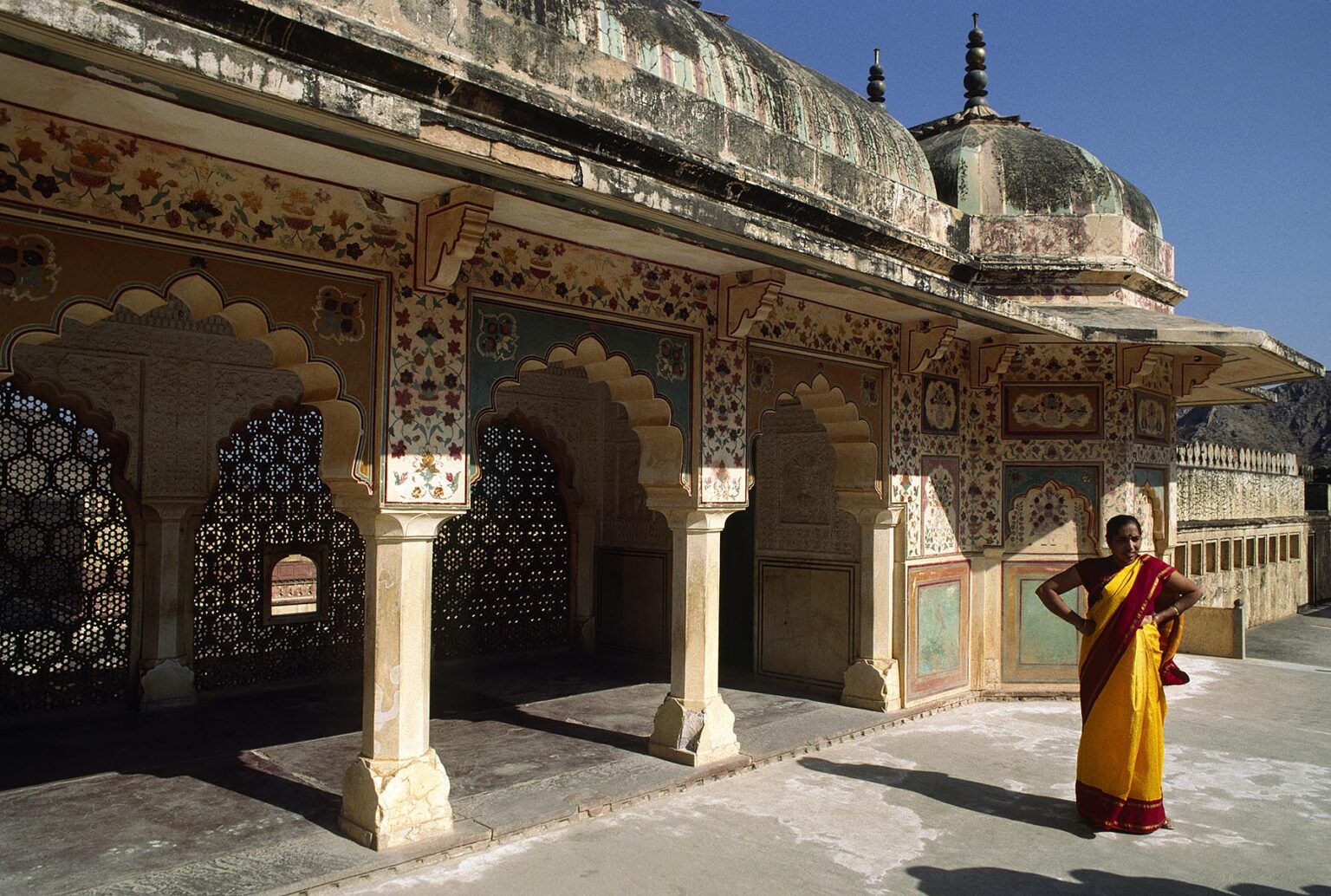 WOMAN wearing a SARI next to WALKWAY with FLORAL PATTERNS on the walls of the AMBER FORT near JAIPUR - RAJASTHAN, INDIA