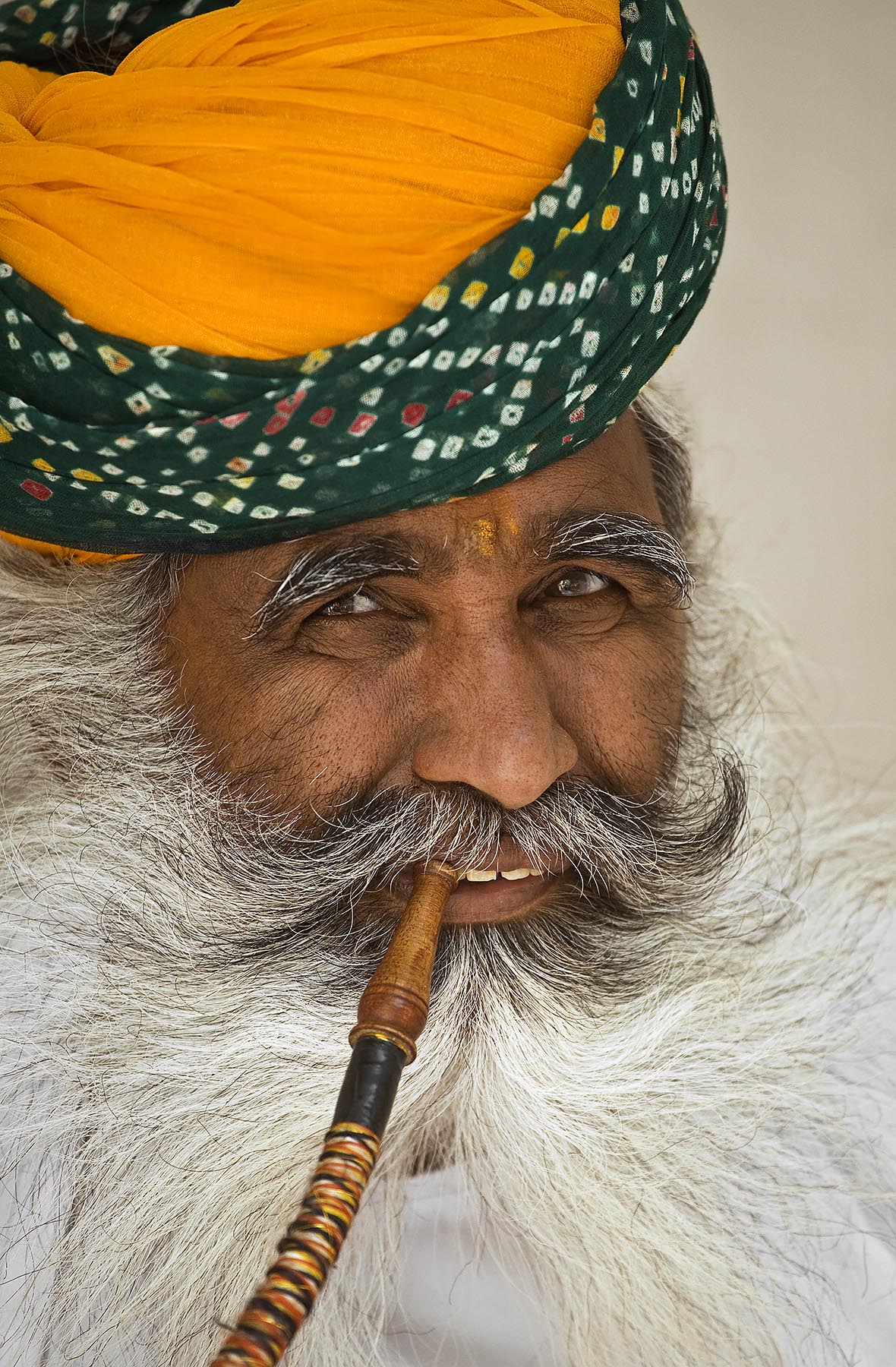 A turbaned Rajasthani man demonstrates the use of a HOOKAH PIPE in the MEHERANGARH FORT - JOHDPUR, RAJASTHAN, INDIA