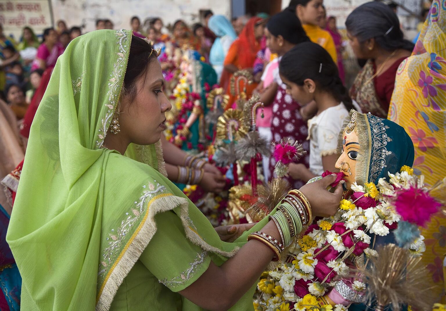 A Rajasthani woman makes a flower offerting to Shiva's wife PARVATI at the GANGUR FESTIVAL also known as the MEWAR FESTIVAL in UDAIPUR - RAJASTHAN, INDIA