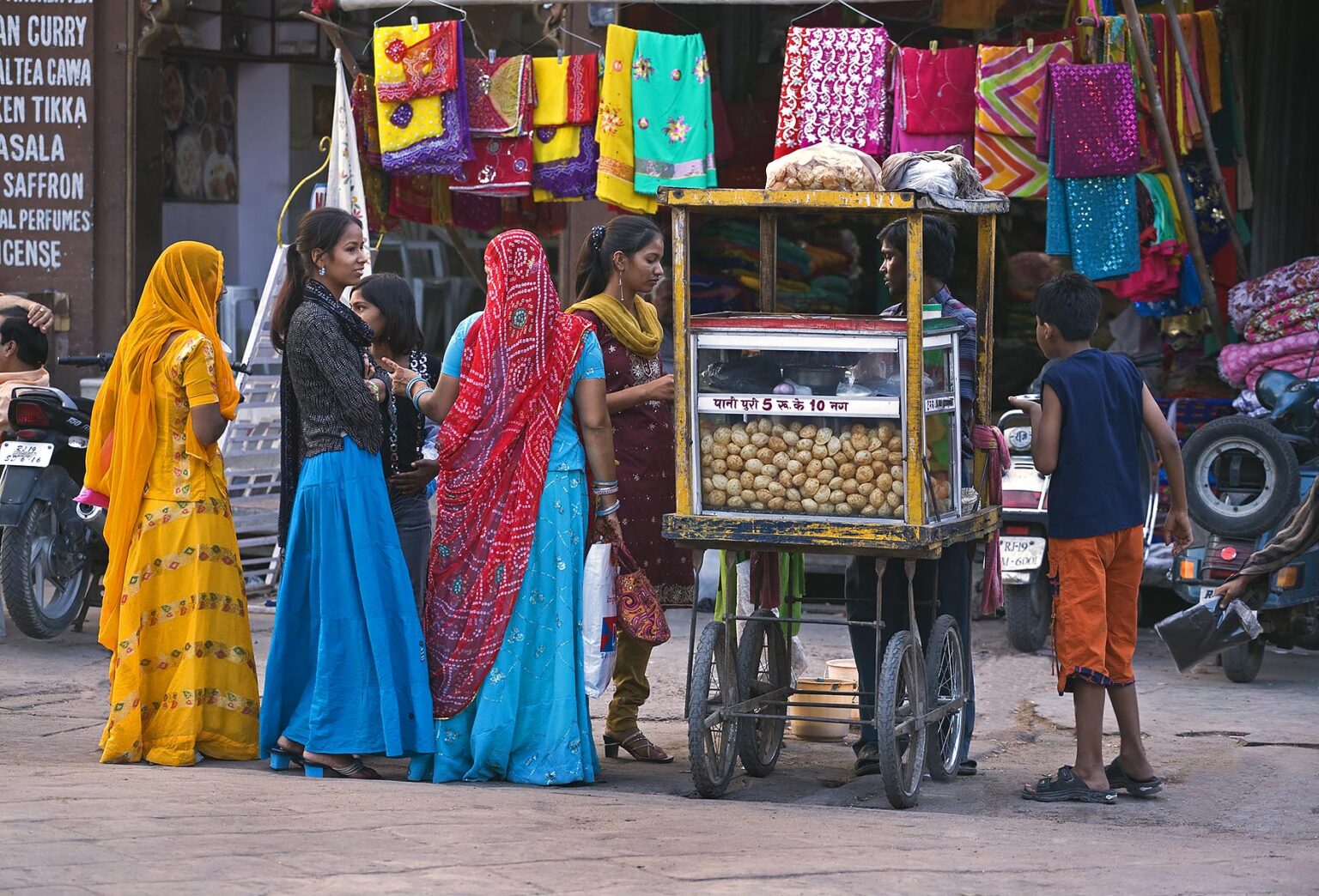 Young girls buy a snack at a food stall in SARDAR MARKET CIRDIKOT in JOHDPUR known as the BLUE CITY - RAJASTHAN, INDI