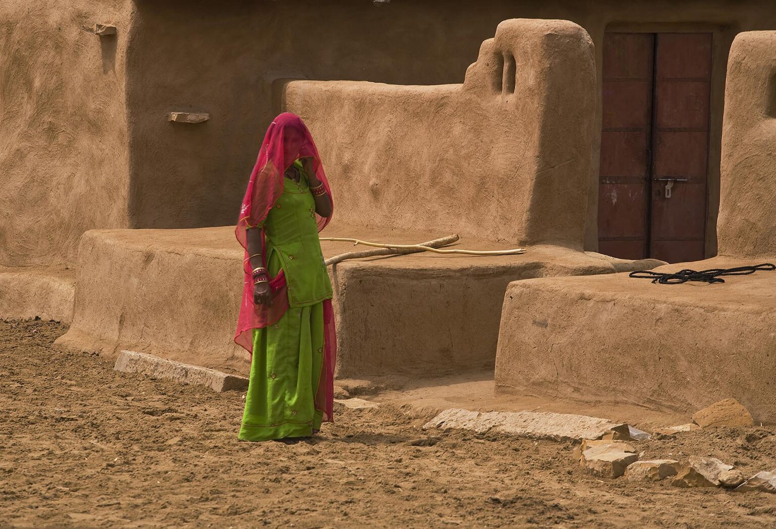 A BANJARI TRIBAL WOMAN and her classic MUD HOUSE in a village in the THAR DESERT near JAISALMER - RAJASTHAN, INDIA