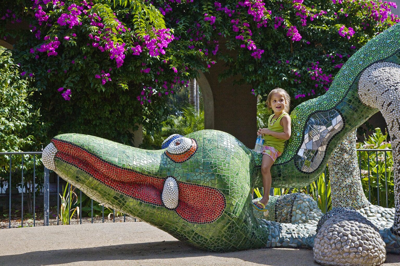 A young girl on a DRAGON SCULPTURE in front of the MINGEI INTERNATIONAL MUSEUM is located in BALBOA PARK SAN DIEGO, CALIFORNIA
