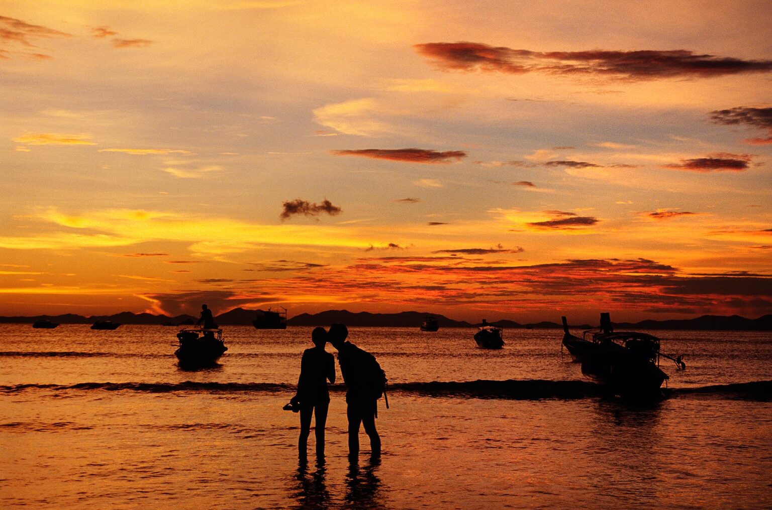 A SUNSET silhouettes a couple at KRABI BEACH on the ANDAMAN SEA in southern THAILAND
