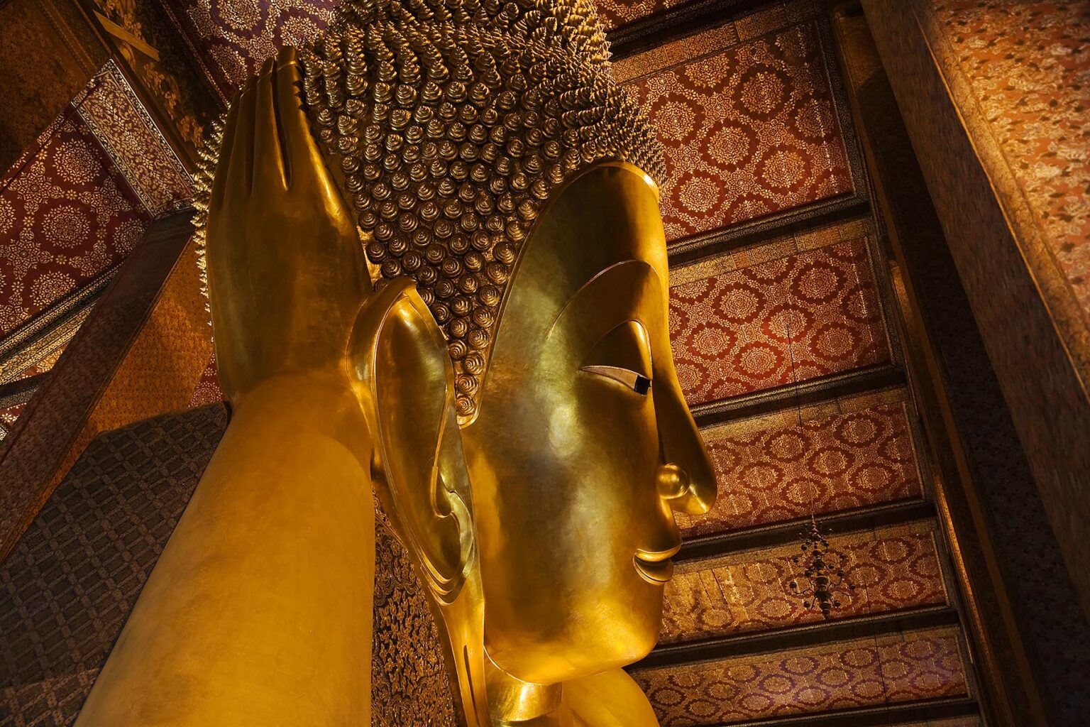 The gilded head of the largest RECLINING BUDDHA in THAILAND (46 meters long) which is found at the THERAVADA BUDDHIST TEMPLE of WAT PO - BANGKOK, THAILAND