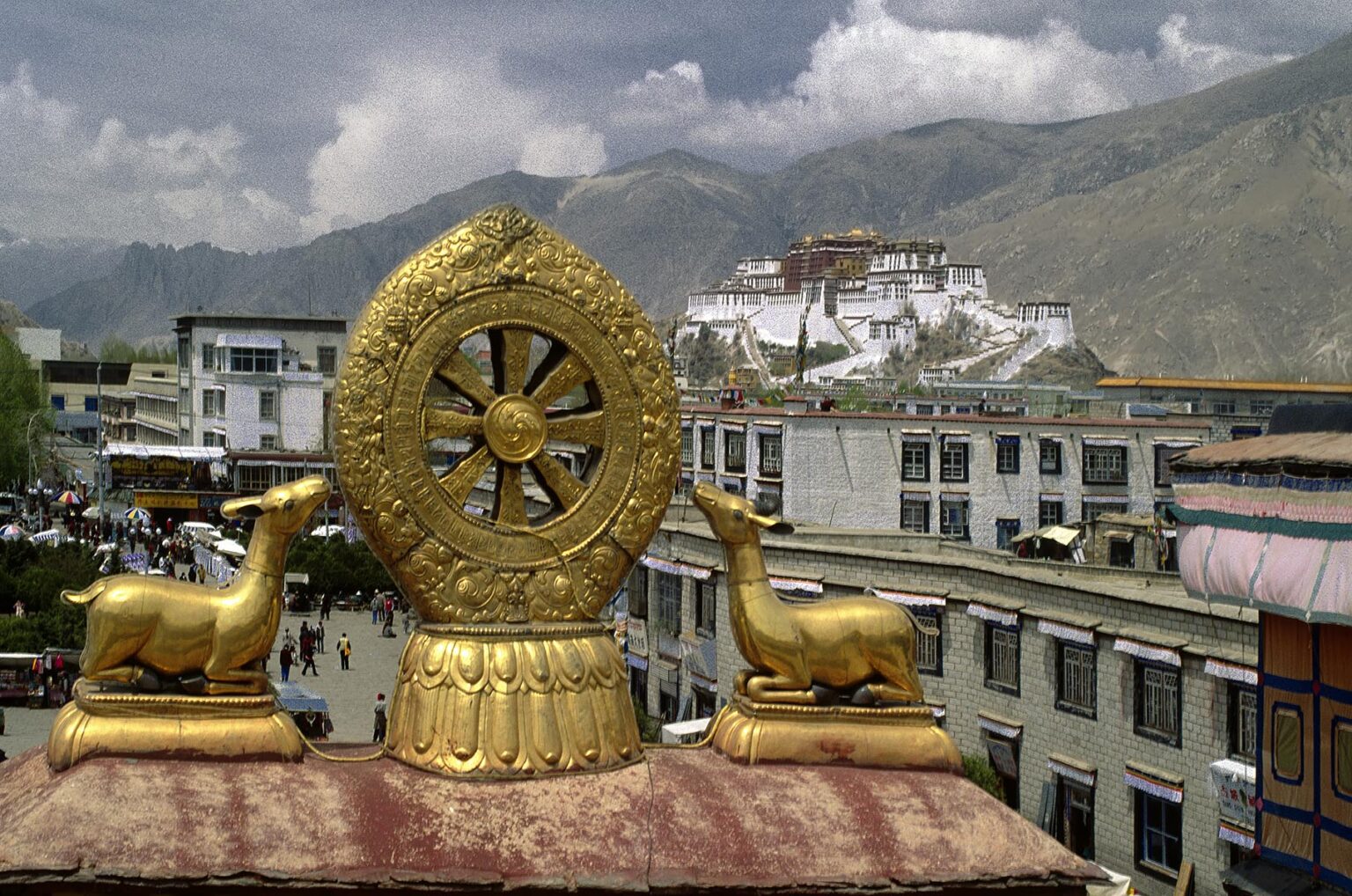 The POTALA is visible through the GOLDEN DHARMA WHEEL and DEER which adorn the roof of the JOKHANG - LHASA, TIBET