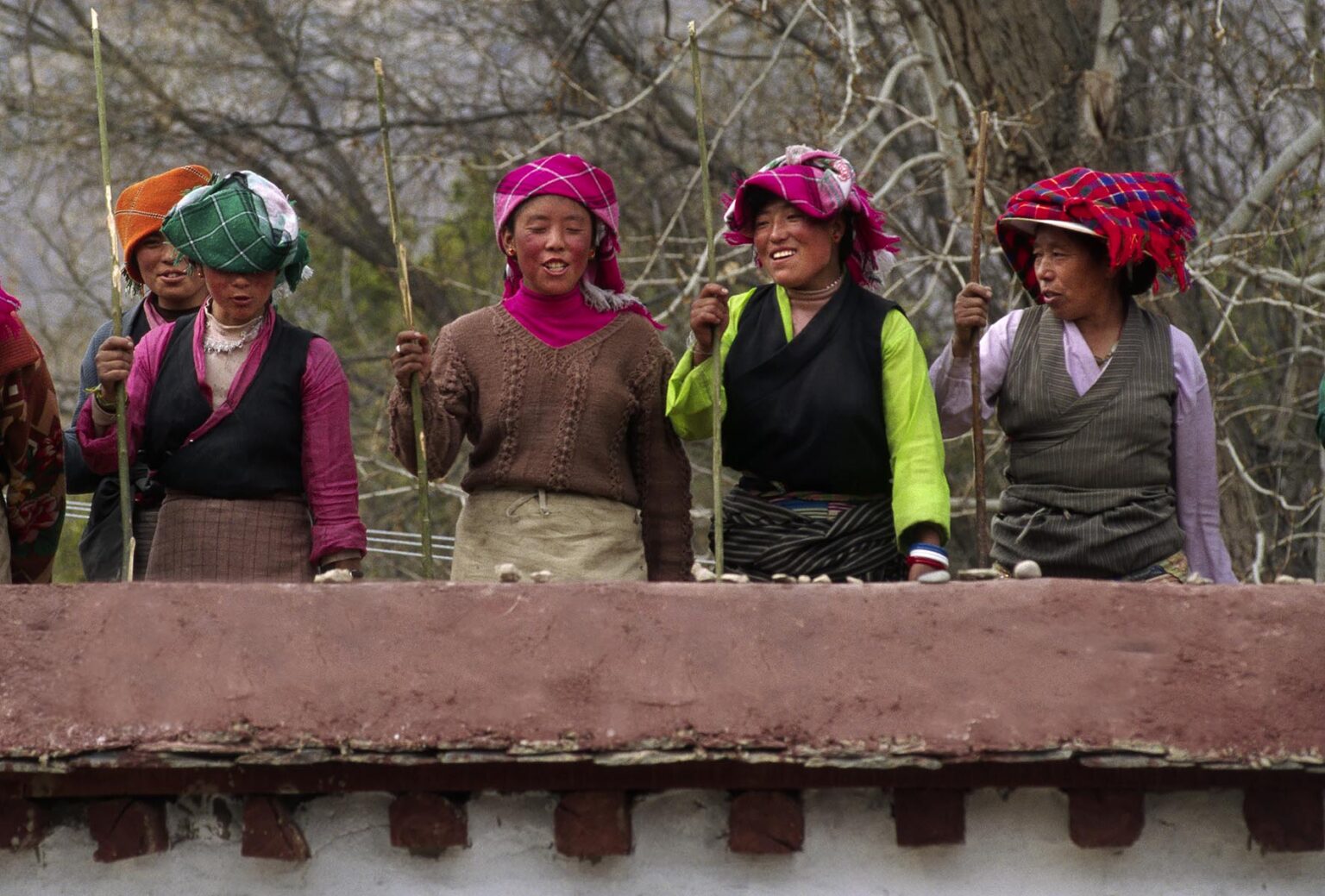 TIBETAN WOMEN dance & sing while packing a roof at the NORBULINGKA which was the Dalai Lama's Summer Palace - LHASA, TIBET