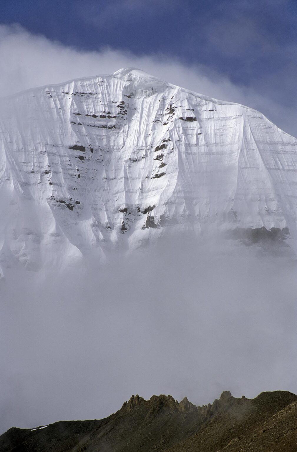 The mist enshrouded North Face of MOUNT KAILASH (6638 M) is a sacred site for BUDDHIST and HINDU  PILGRIMS - TIBET