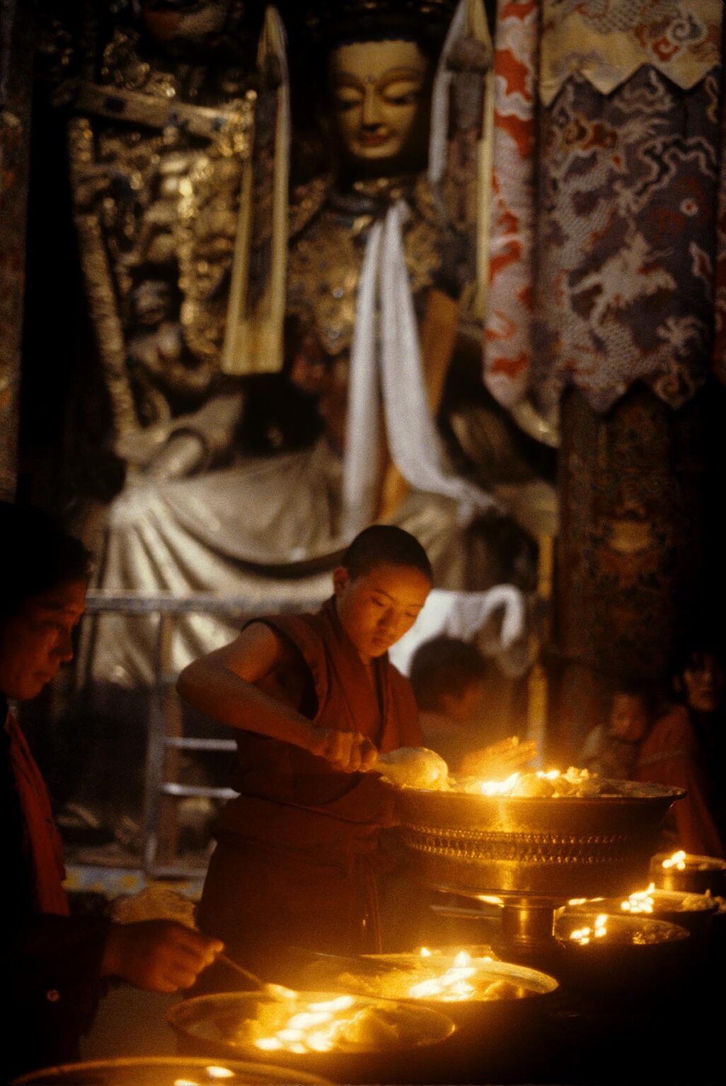 A MONK lights butter lamps in the JOKHANG, TIBET'S holiest temple, built by KING SONGTSEN GAMPO in the 7th Century - LHASA, TIBET