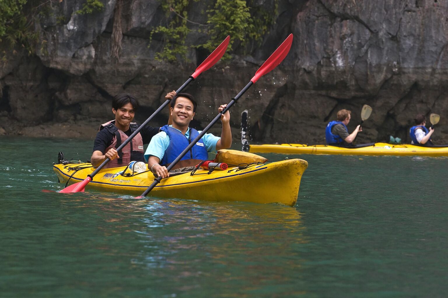 Kayakers exploring SURPRISING CAVE in the calm waters of HALONG BAY - VIETNAM