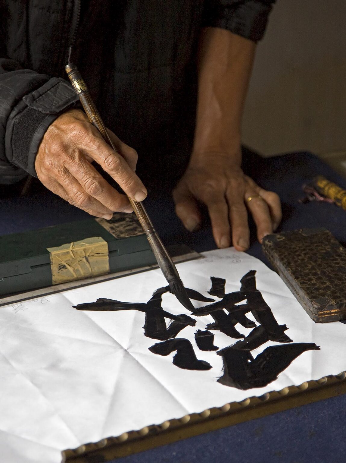 An artist paints traditional characters inside the NGOC SON TEMPLE in the old quarter - HANOI,  VIETNAM