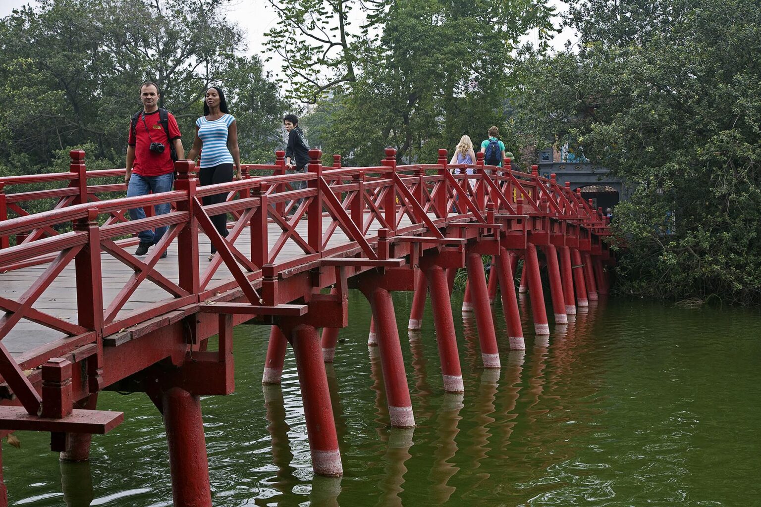 Tourists cross the The HUC BRIDGE  over the HO AN KIEM LAKE in the old quarter - HANOI, VIETNAM
