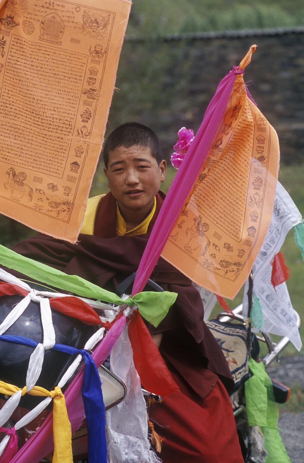 Buddhist monk with motorcycle  decorated with  katoks and prayer flags - Kham, (E. Tibet), Sichuan Province, China