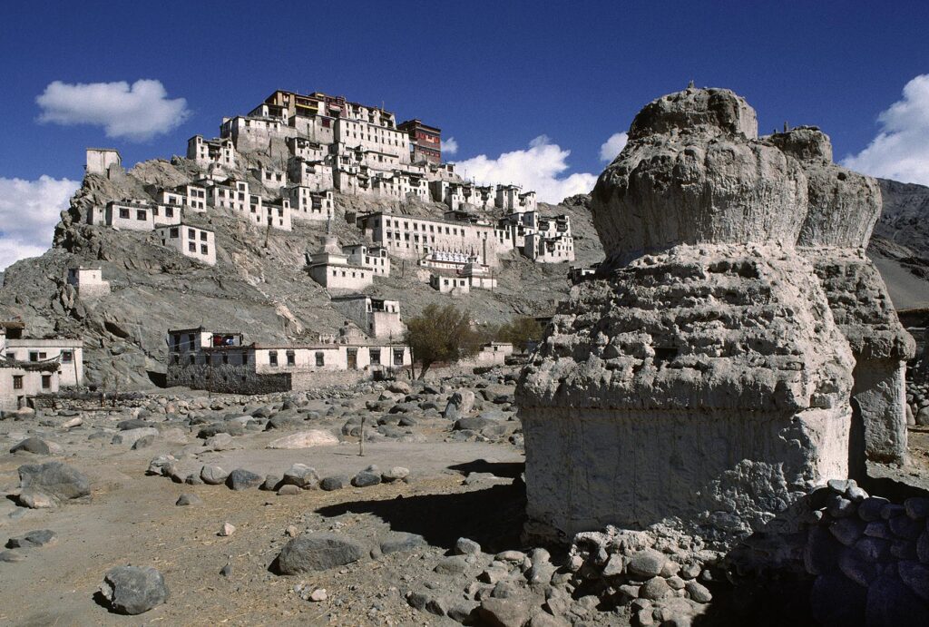 TIKSE GOMPA (monastery), built in the 15th century, rises above BUDDHIST CHORTENS - LADAKH, INDIA