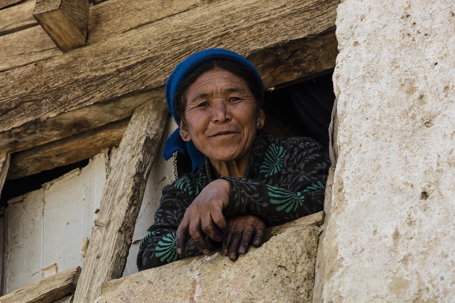 A woman smiles from her window in Nyerak village in the ZANSKAR RIVER GORGE - ZANSKAR, LADAKH, INDIA