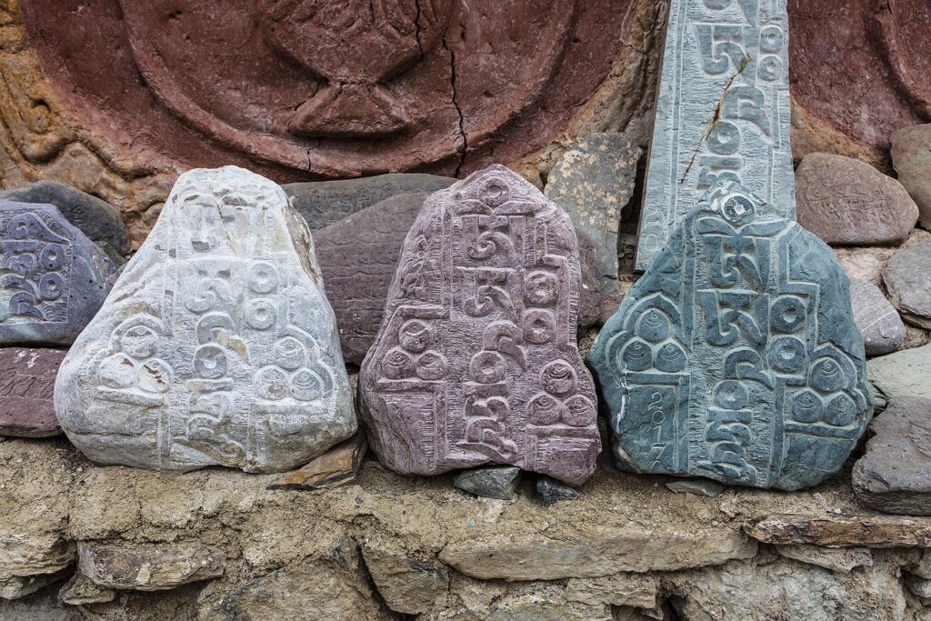 BUDDHIST MANI STONES carved with prayers surround a stupa at LAMAYURU MONASTERY founded by NAROPA - LADAKH, INDIA