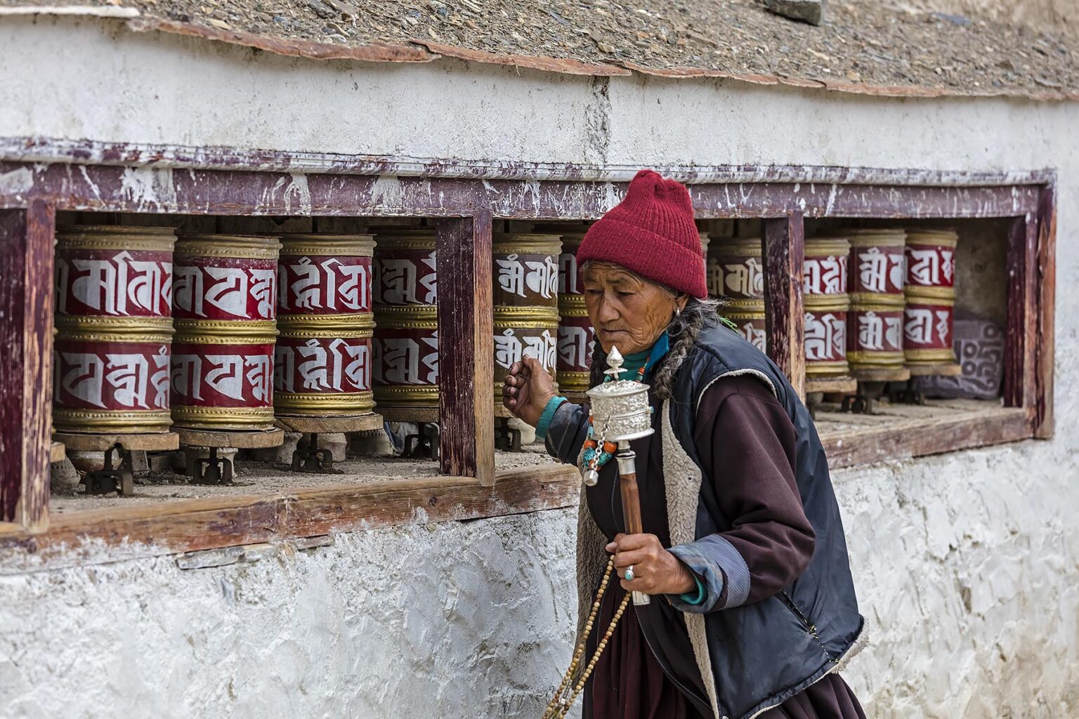A Ladakhi woman turs the PRAYER WHEELS at LAMAYURU MONASTERY - LADAKH, INDIA