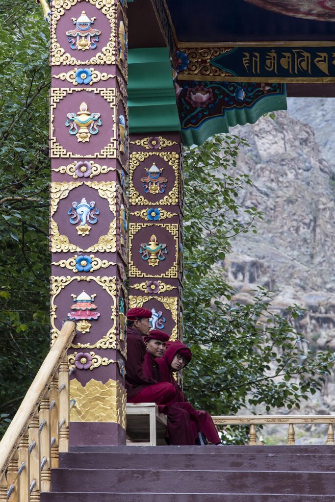 Three monks sit at the entry of HEMIS MONASTERY - LEH VALLEY, LADAKH