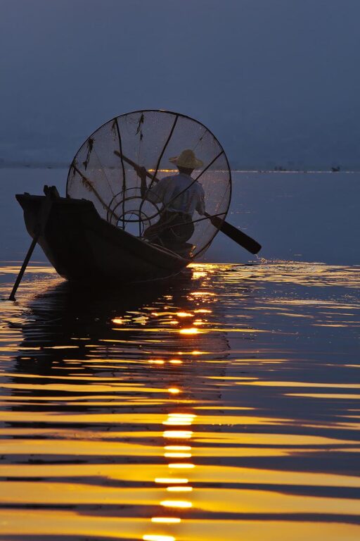 FISHING at dawn is still done in the traditional way with small wooden boats, fishing nets and leg rowing - INLE LAKE, MYANMAR