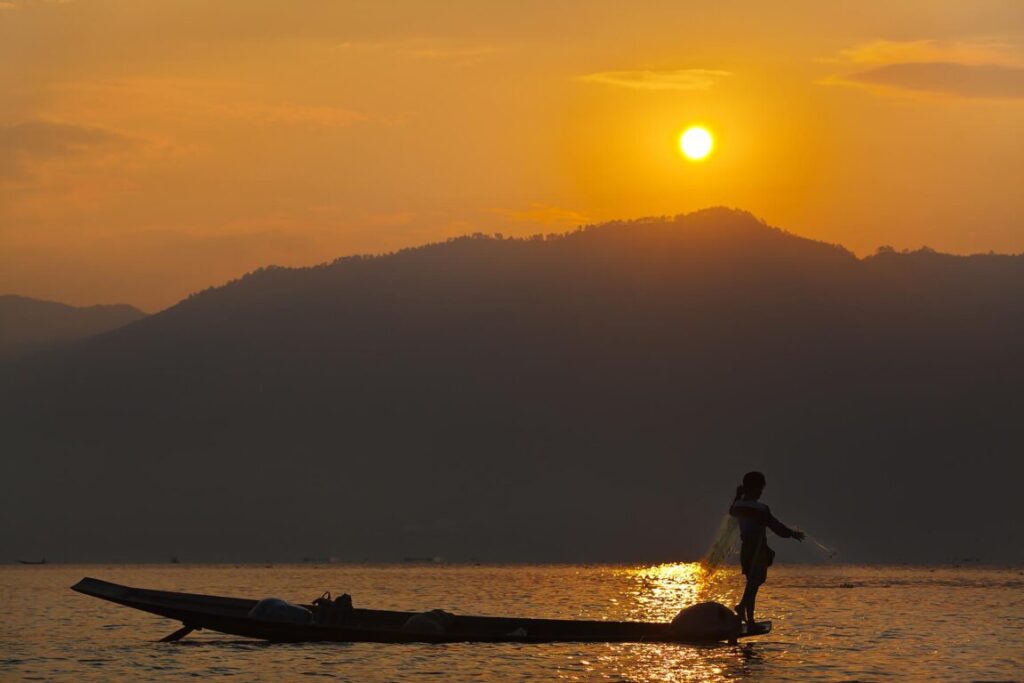 FISHING at dawn is still done in the traditional way with small wooden boats, fishing nets and leg rowing - INLE LAKE, MYANMAR
