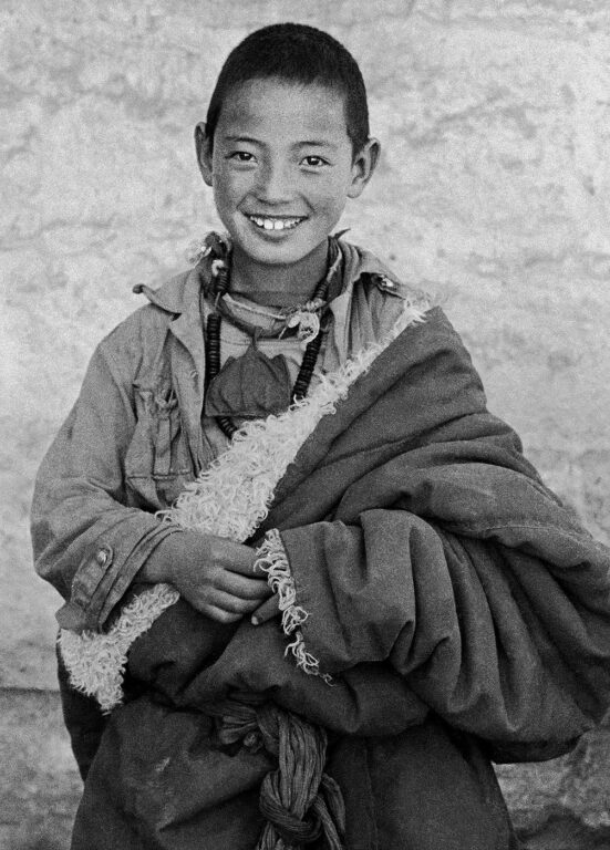 A young Tibetan monk in a sheep skin chuba - SERA MONASTERY, LHASA, TIBET